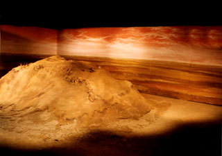 La struttura scenica. Gli spettatori, seduti in alto, si confondono nel buio.