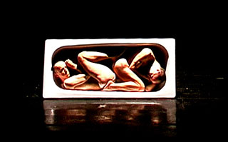 Una vecchia vasca da bagno trasformata in un utero contenente due gemelli nello spettacolo Nella città di K